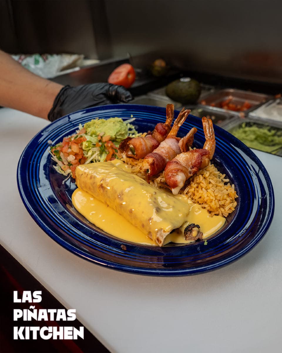 Signature cheese-smothered burrito with bacon-wrapped shrimp at Las Piñatas Kitchen Tomball