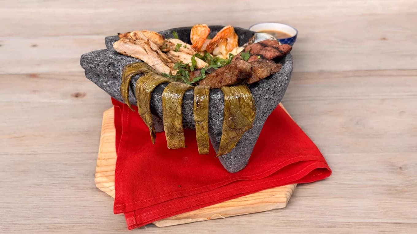 Traditional molcajete stone bowl with grilled meats and shrimp — authentic Mexican cuisine in Tomball